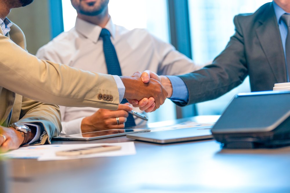 Businessmen shaking hands at the board room table..